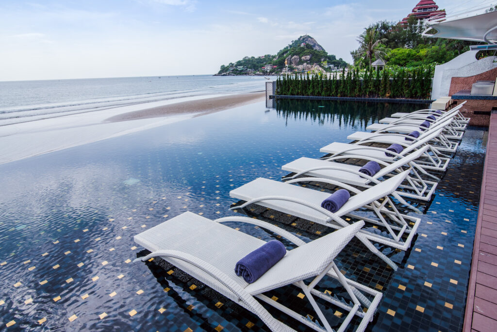 Sun loungers set in the infinity pool facing the sea and Khao Takiab hill